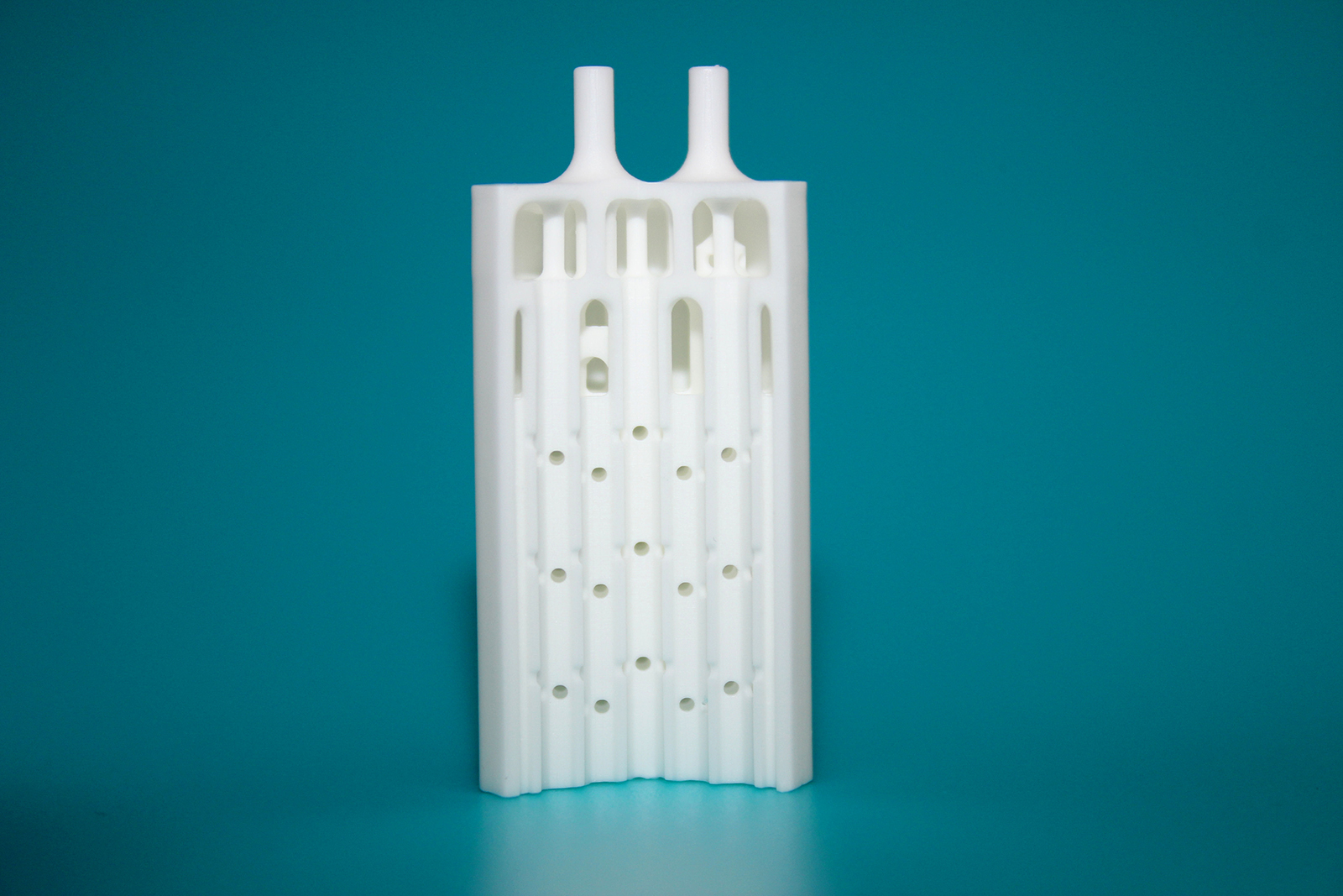 Cut through a ceramic microreactor which was manufactured additively: the complex channels as well as the fluidic connections at the top were printed together with the whole component.