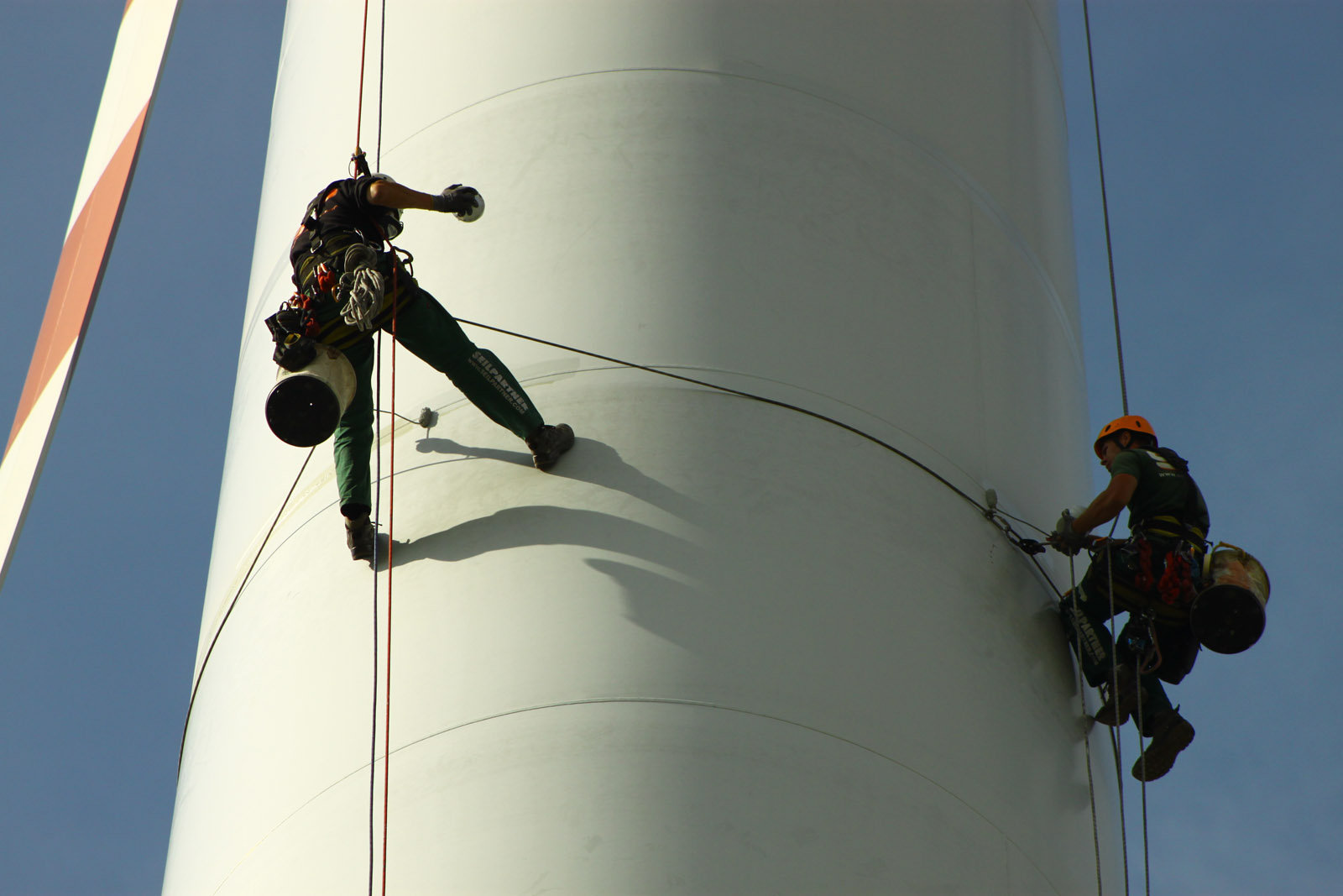 Industrial climbers abseiling down a rotor blade.