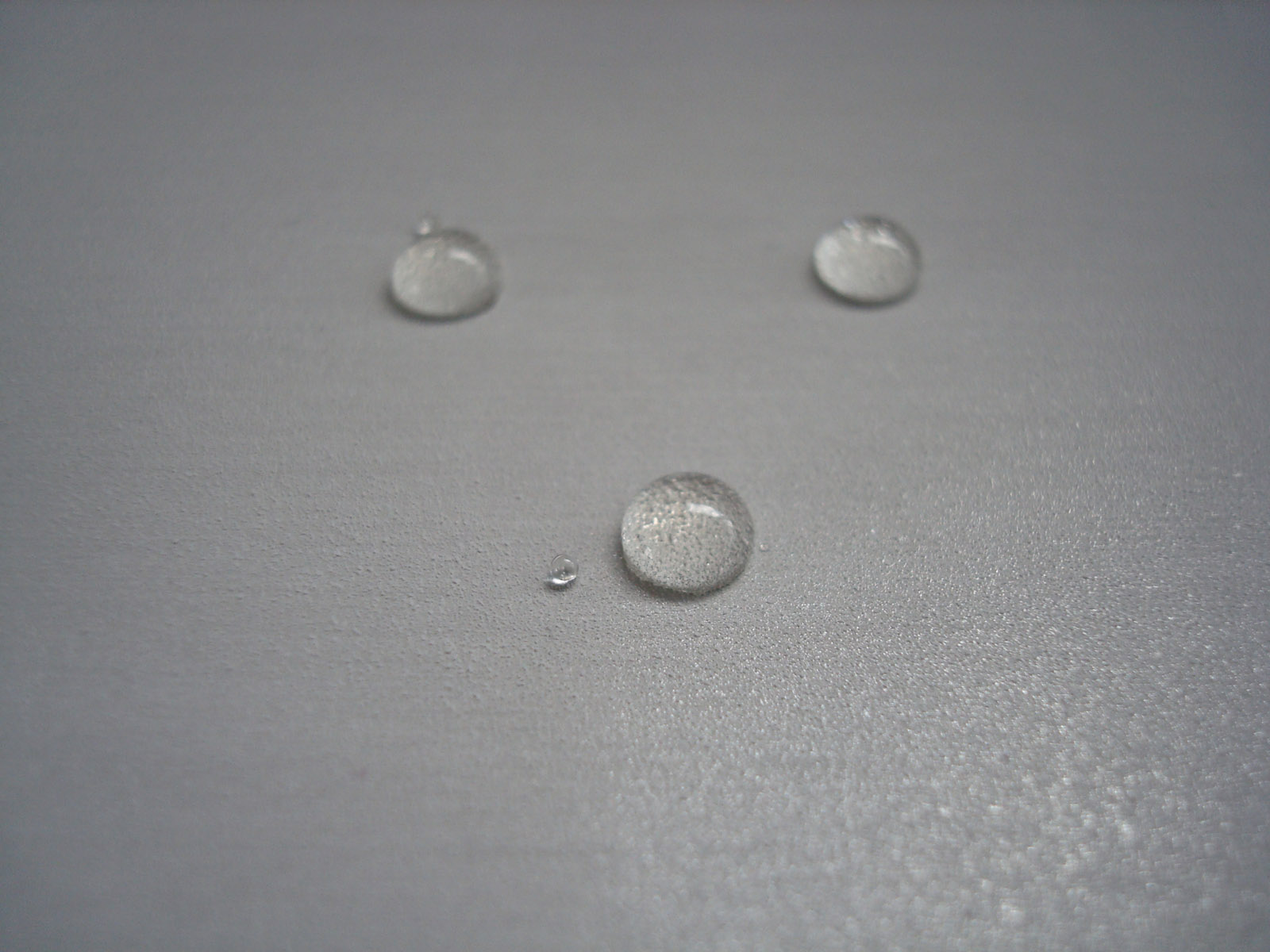 Drops of oil on a super hydrophobic and oleophobic coating on stainless steel.