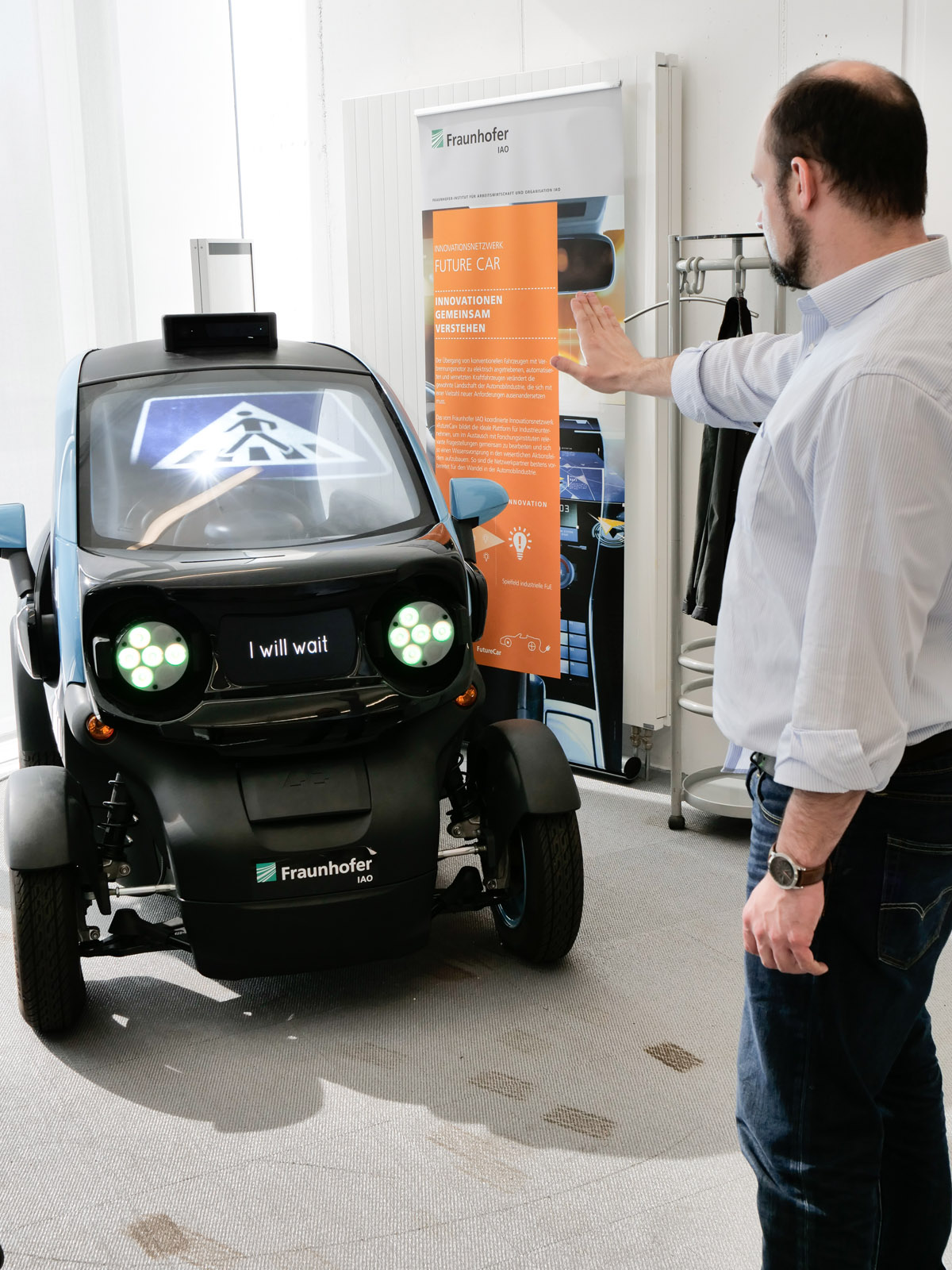 The Mobility Innovation Lab is a modern research facility for prototyping and creative workshops. A converted car interacts with a pedestrian.
