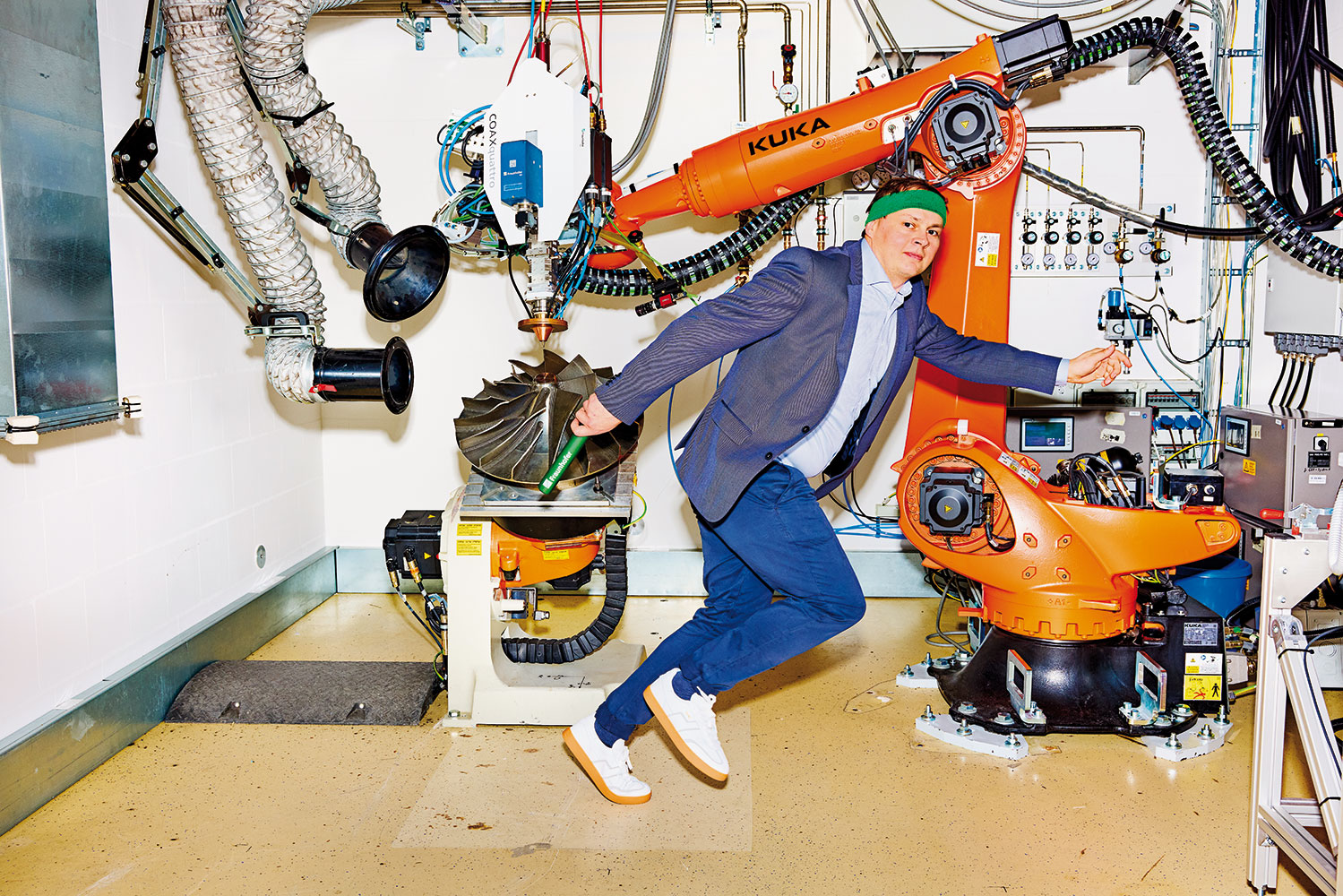 Fraunhofer IWS-Wissenschaftler Holge Hillig im inszenierten Staffellauf mit Staffelstab in der Hand vor einem Schweißroboter.