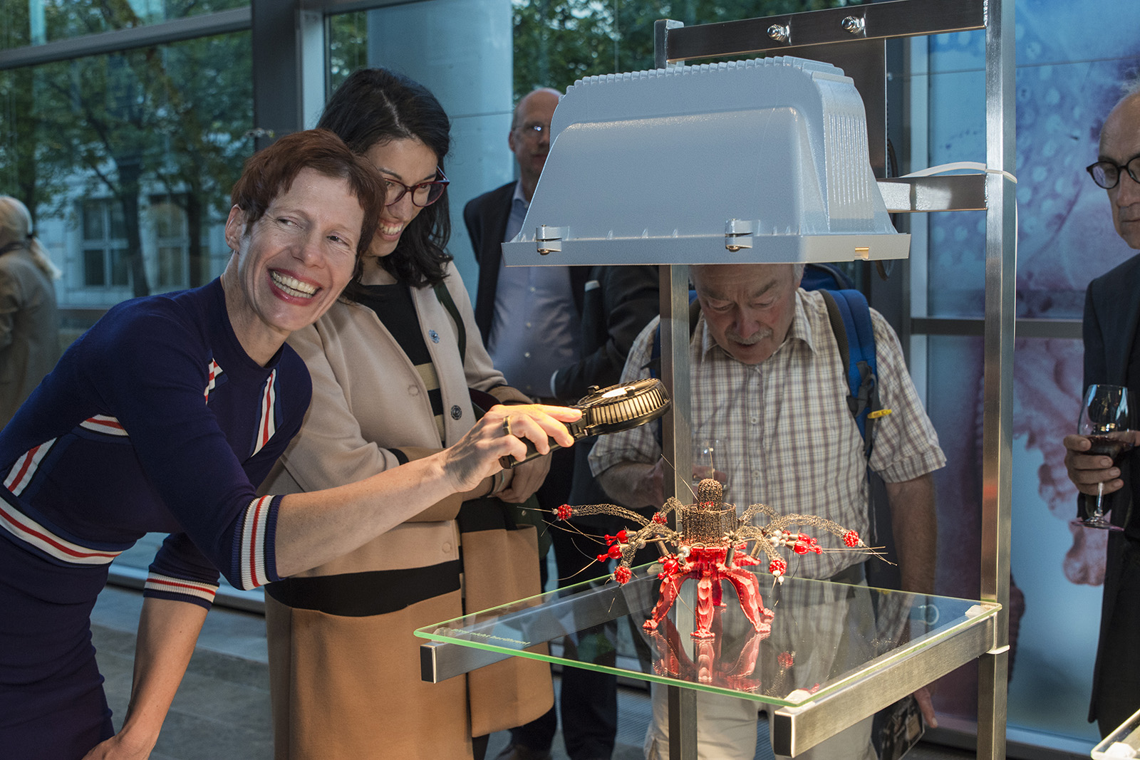 Beate Eismann demonstriert auf der Vernissage FÖNIKUS den Besuchern.  Wärmezufuhr bewirkt, dass die Drähte aus FGL ihre ursprünglich gestreckte Form einnehmen – der FÖNIKUS bewegt sich und wirkt lebendig.