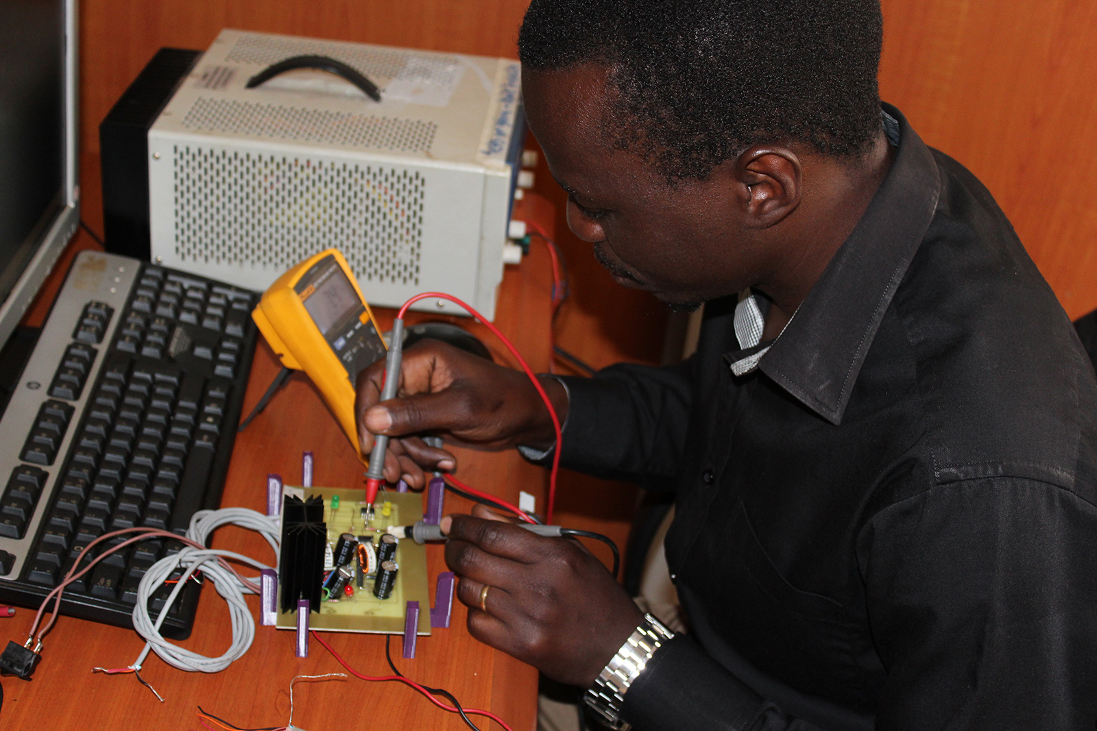 Elektrotechniker Ronald Kyeyune des UIRI testet eine elektronische Schaltung für die Spannungsversorgung des Schwerkraftinfusionssystems ECGF-IS.