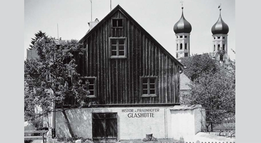 Die historische Glashütte vor den Türmen des Klosters Benediktbeuern.