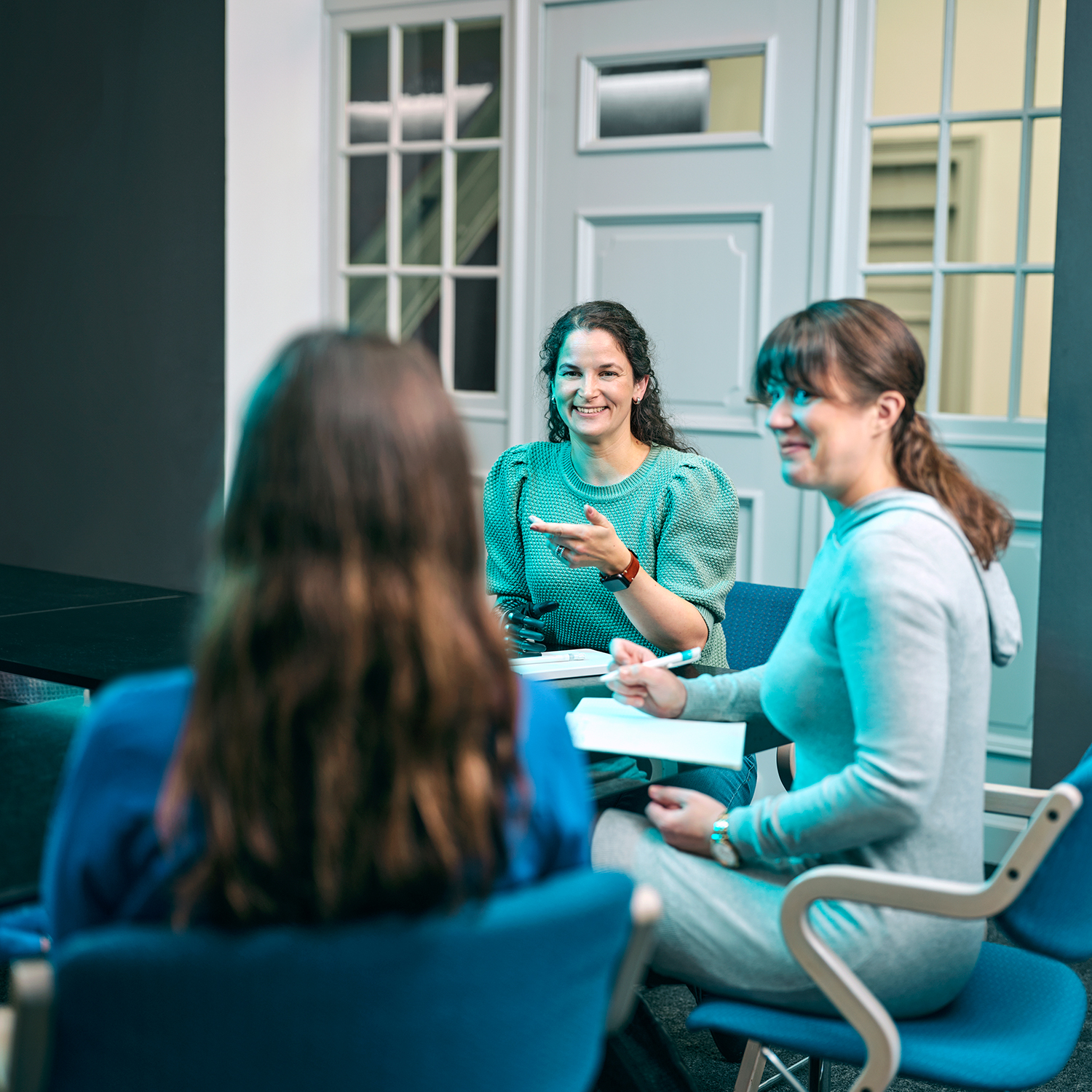 Three women sit together and talk.