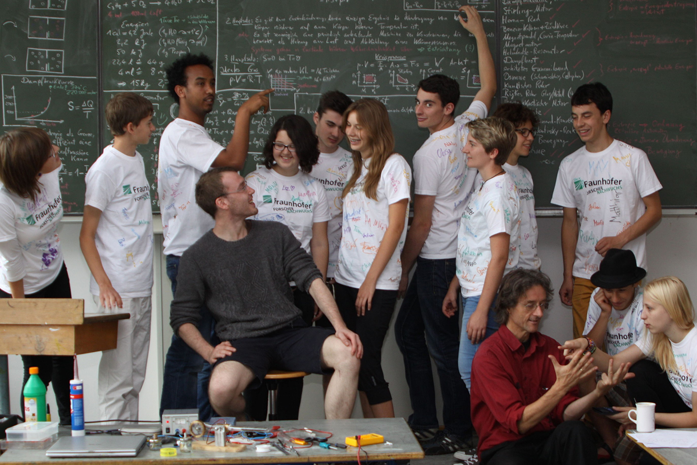 Many people stand in front of a blackboard.