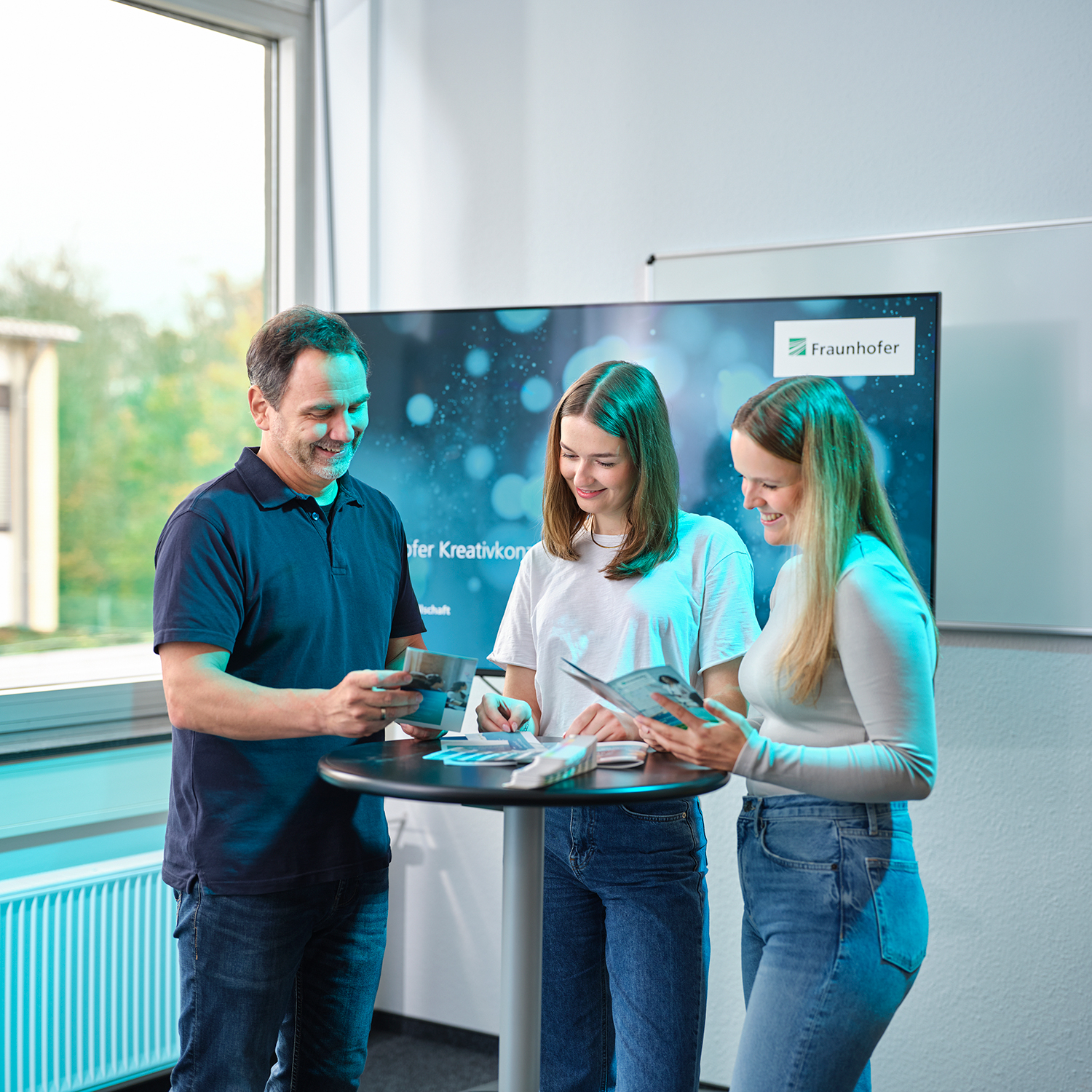 Two younger women and a man looking at a tablet.
