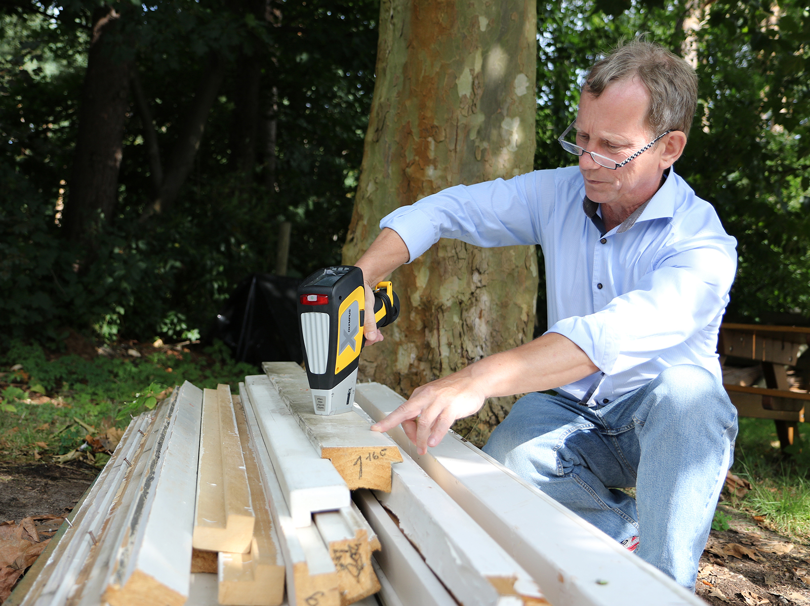 Physicist using a hand-held X-ray fluorescence to test sections of salvaged window scantlings for the presence of inorganic wood preservatives.