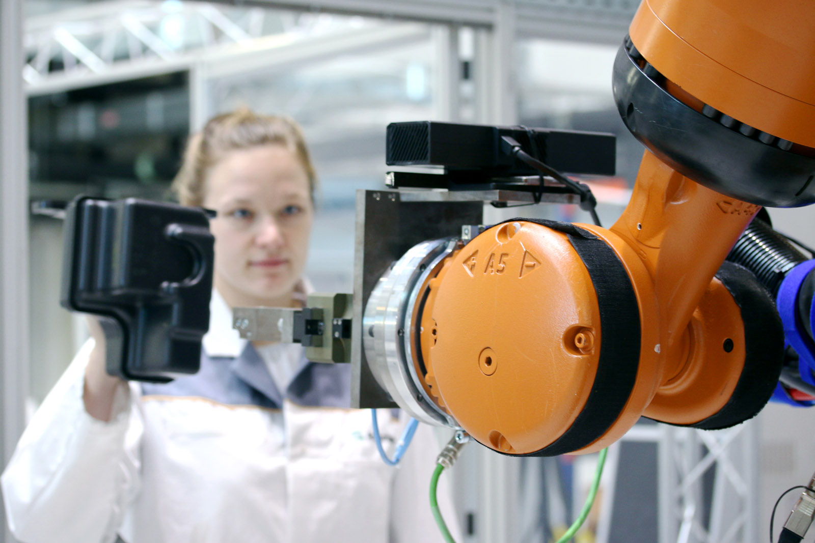 The robot detects the component in the worker’s grasp and cautiously follows it until she hands it over.