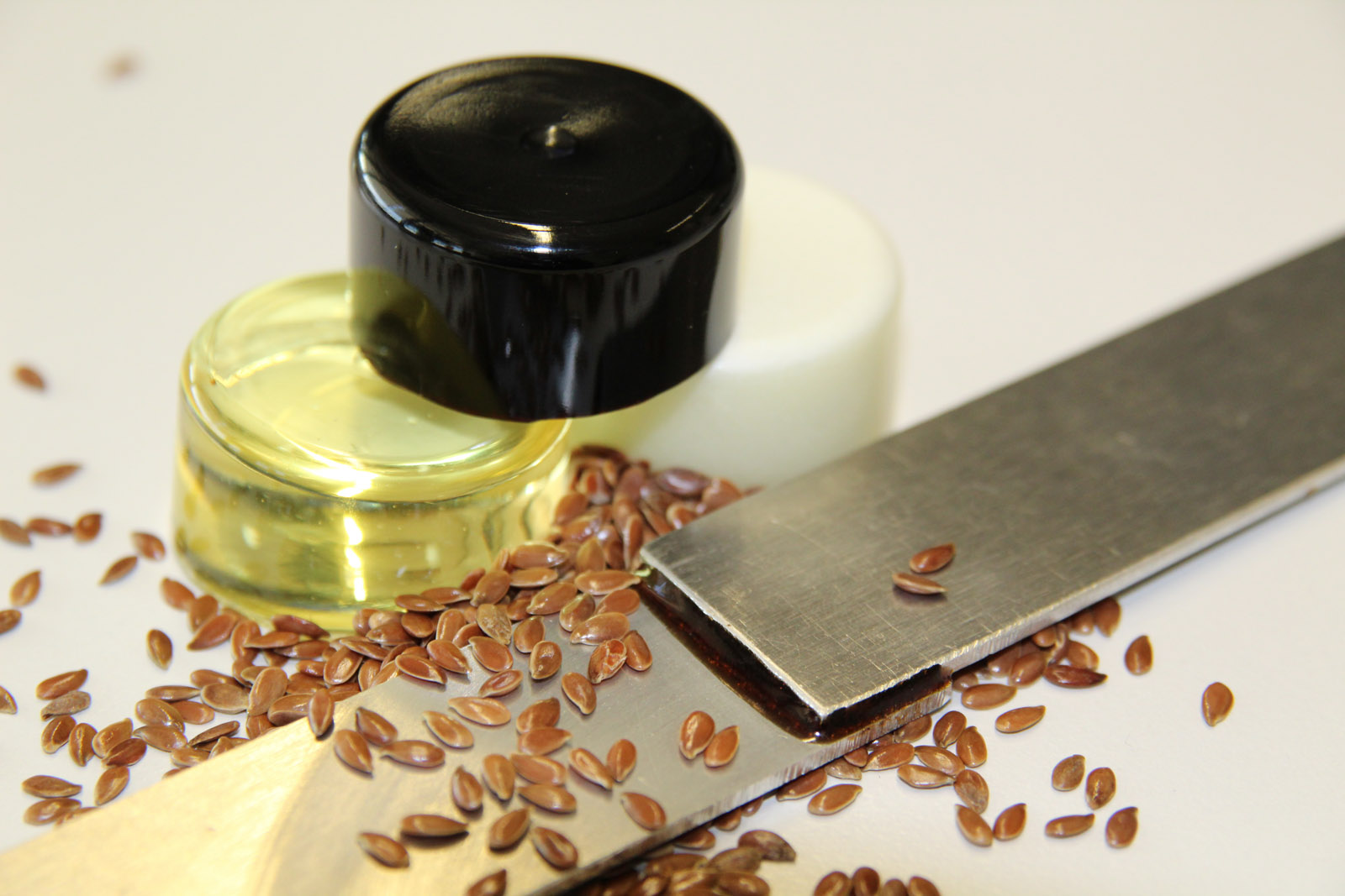 Two metal parts joined using the new, sustainably produced adhesive. Behind them: three pots containing the ingredients of the adhesive – the liquid hardener (yellow), the paste hardener (white) and the lignin organic solvent (black).