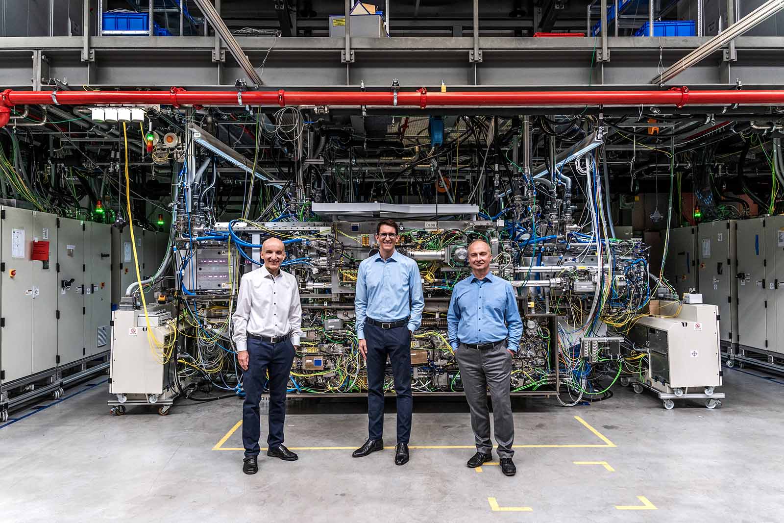 The team of experts in front of the world's strongest pulsed industrial laser, which is used for light generation to enable EUV lithography (from left): Dr. Peter Kürz from the ZEISS SMT segment, Dr. Michael Kösters from TRUMPF Lasersystems for Semiconductor Manufacturing, and Dr. Sergiy Yulin from the Fraunhofer Institute for Applied Optics and Precision Engineering (IOF).