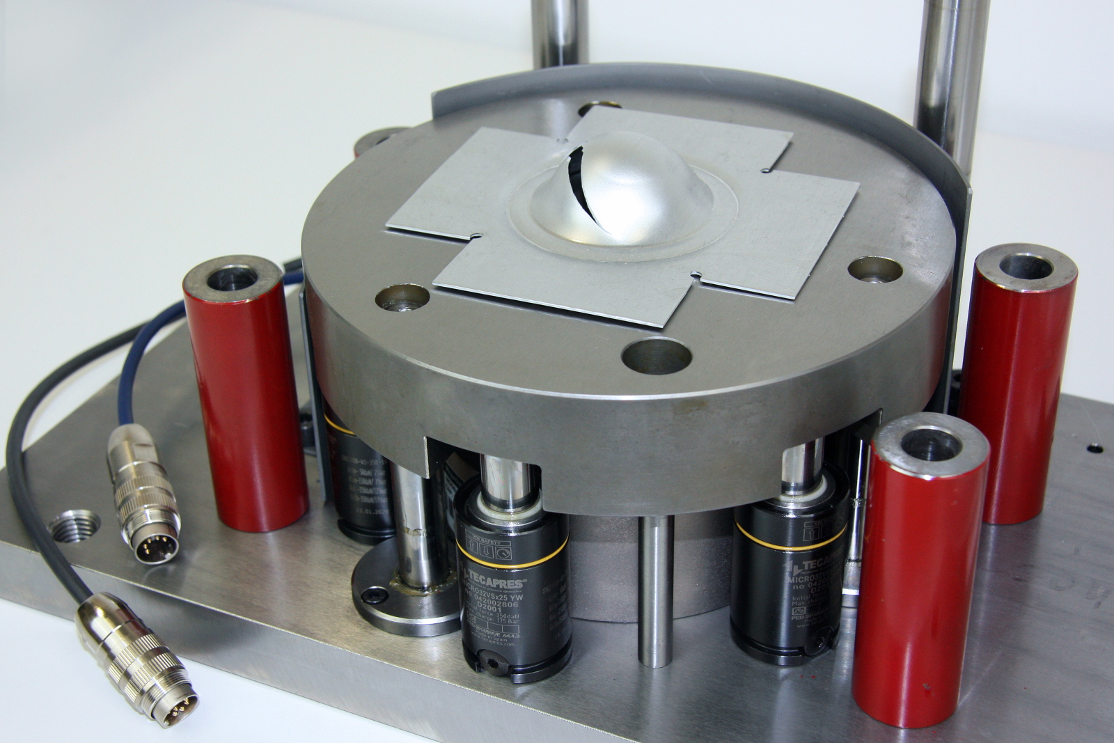 In the testing machine, a hemispherical stamp pushes the component down to a defined depth. The  force-displacement profile is analyzed to allow detailed conclusions to be drawn about the quality of the material.