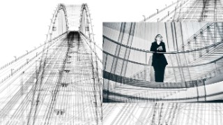 Informatikerin TagIine Treichel vom Fraunhofer IESE, lehnend an einem Inhouse-Geländer, im Hintergrund ist eine Konstruktionszeichnung einer Brücke großformatig an die Wand projiziert.