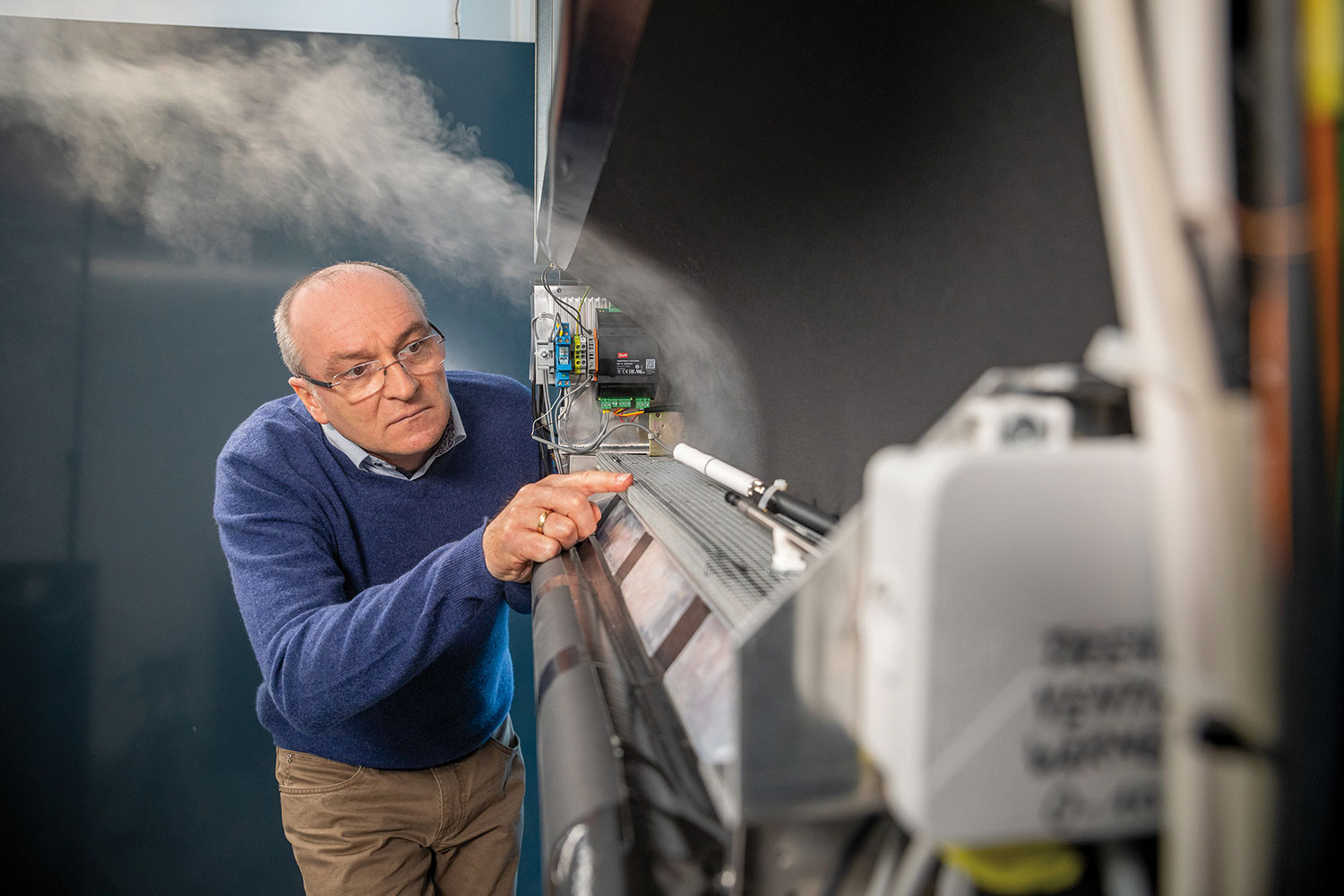 While testing the  RE modular  facade, Herbert  Sinnesbichler of  Fraunhofer IBP  uses a fog  machine to  visualize airflows.